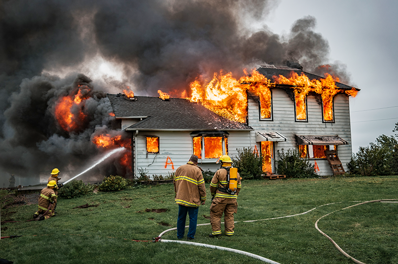 a house on fire being controlled by fire fighters